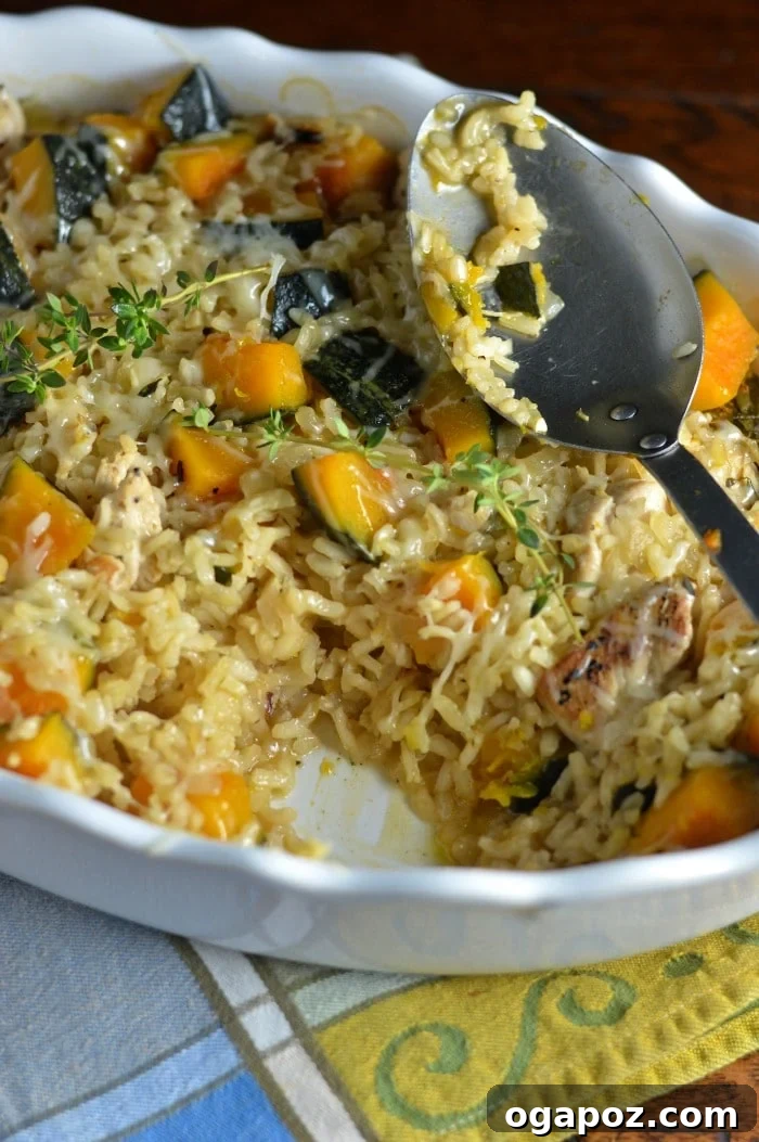 Creamy Kabocha Squash Risotto with Baked Chicken 3 A close-up of Baked Chicken Kabocha Squash Risotto in a white bowl, garnished with fresh thyme, with a spoon resting beside it, highlighting its rich texture.