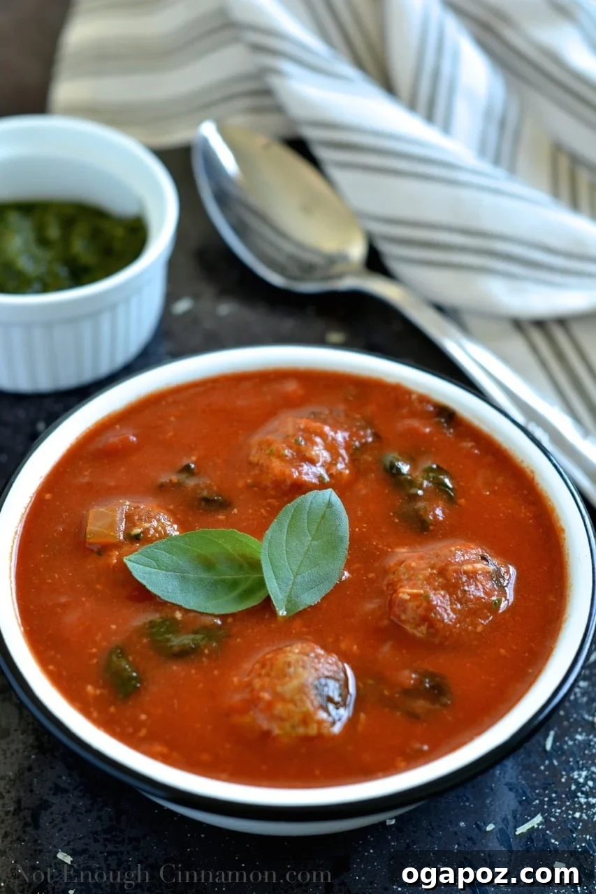 Vibrant Spinach and Tomato Comfort 3 A close-up of Spinach and Tomato Soup with meatballs and a spoon, highlighting its creamy texture and rich ingredients.