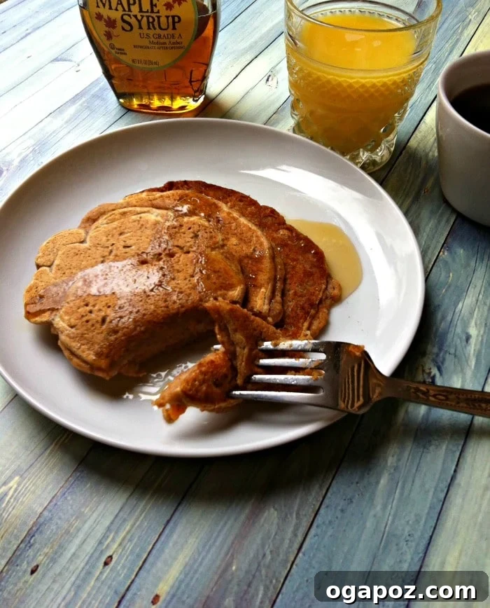 Golden Cinnamon Sweet Potato Pancakes 4 Close-up of golden brown Sweet Cinnamon Potato Pancakes stacked high, drizzled with syrup and a dusting of cinnamon.