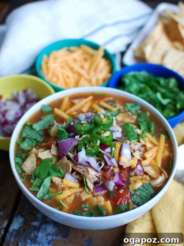 Effortless Fiesta Chicken Soup 2 Slow Cooker Chicken Tortilla Soup in a rustic bowl, garnished with fresh cilantro and a lime wedge.