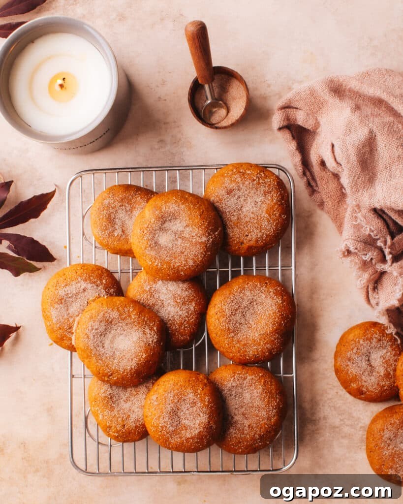 Pillowy Pumpkin Spice Cookies 2 Soft Pumpkin Cookies arranged on a kitchen counter with a flickering candle and decorative fall leaves, creating a cozy autumn ambiance.