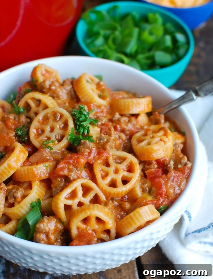 Hearty One-Pot Cheesy Ground Beef Pasta 2 A vibrant close-up of One Skillet Cheesy Hamburger Pasta, garnished with fresh herbs, ready to be served from a rustic skillet.