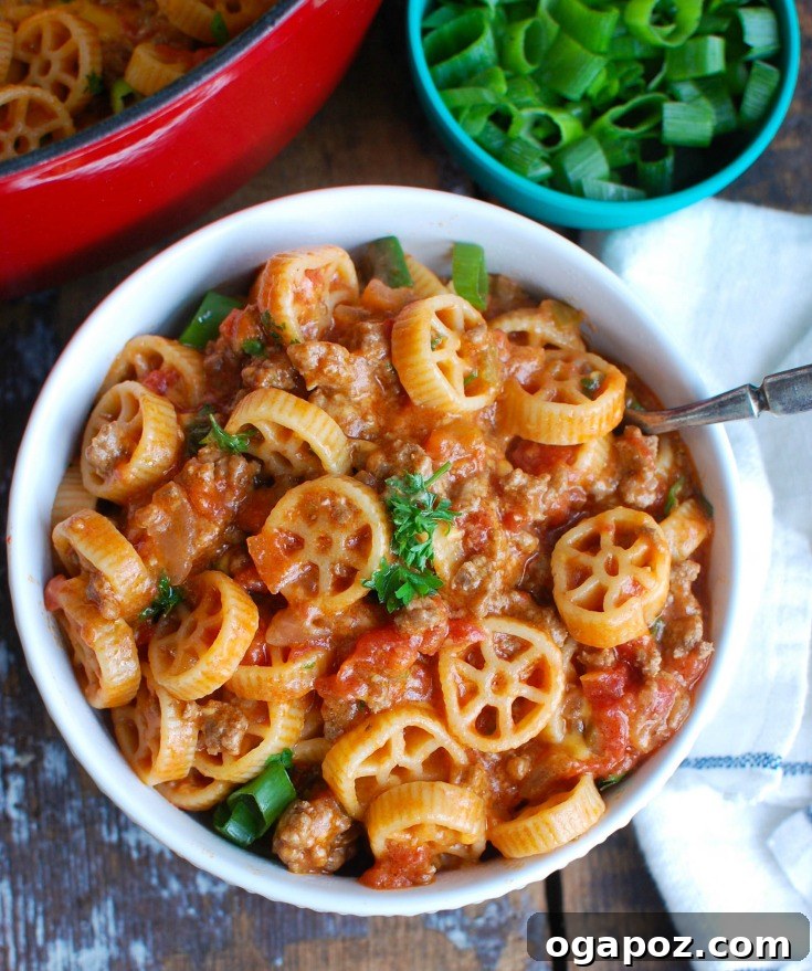Hearty One-Pot Cheesy Ground Beef Pasta 4 A large skillet filled with cooked Cheesy Hamburger Pasta, topped with melted cheese and fresh green onions, ready for serving.