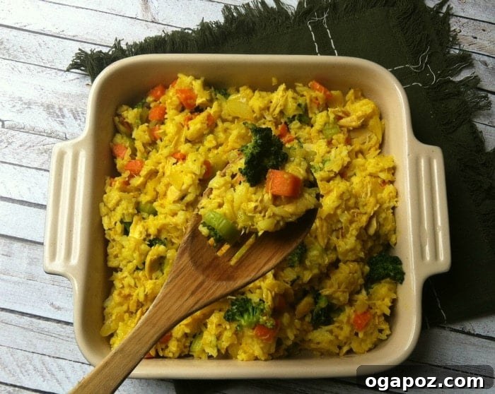A serving of Curried Chicken and Rice Casserole being scooped from the dish with a large spoon, highlighting its creamy texture.