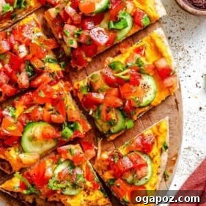 A top-down view of a freshly made Mediterranean Naan Pizza, garnished with herbs and spices, ready to eat.