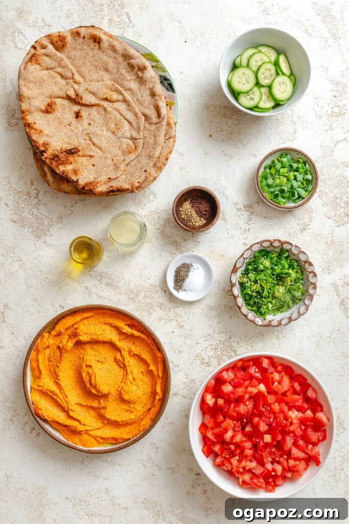 Sun-Kissed Mediterranean Flatbread Pizza 3 A vibrant flat lay of fresh Mediterranean Naan Pizza ingredients, including naan bread, a bowl of hummus, chopped tomatoes, parsley, green onions, and cucumber slices.