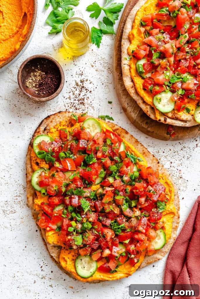 Sun-Kissed Mediterranean Flatbread Pizza 8 A close-up of a Mediterranean Naan Pizza, fully assembled with cucumbers and tabbouleh, ready for a final sprinkle of sumac on a white cutting board.