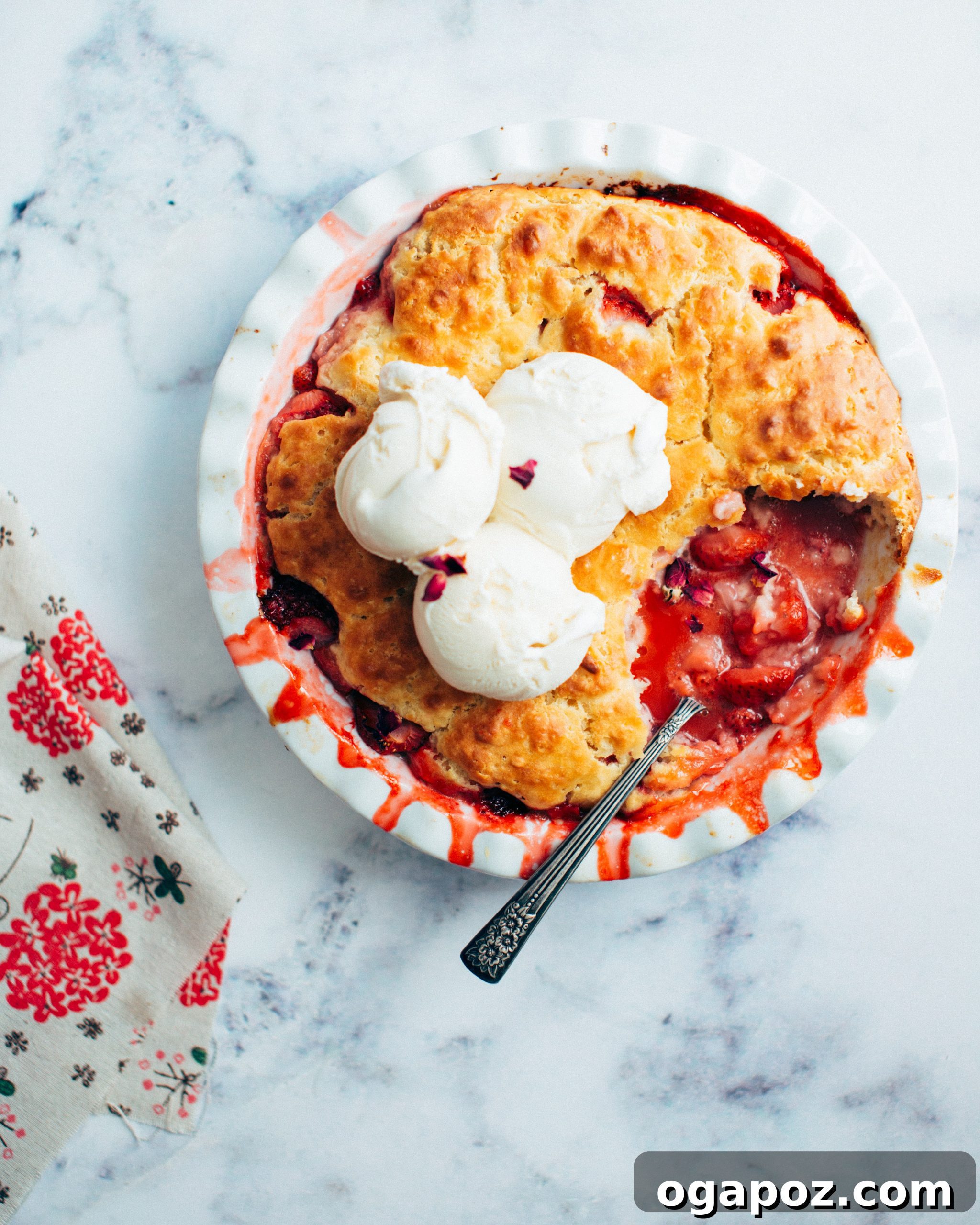 Sweet Strawberry Comfort 2 Baked strawberry cobbler with a spoonful removed and ice cream on top, ready to be served.