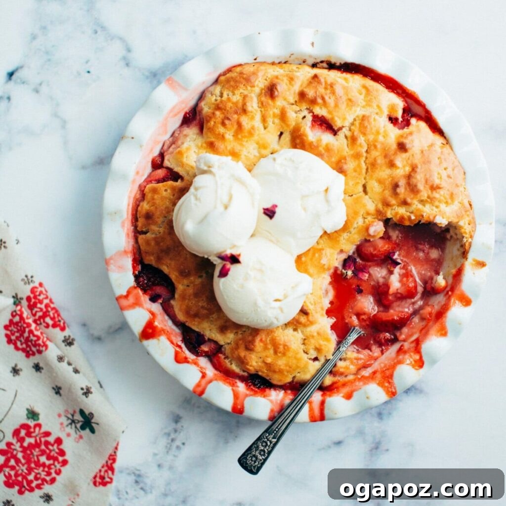 Sweet Strawberry Comfort 6 A serving of warm strawberry cobbler topped with a scoop of vanilla ice cream and a spoon.