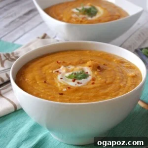 A vibrant bowl of Moroccan Carrot Red Lentil Soup garnished with fresh cilantro and a lemon wedge.