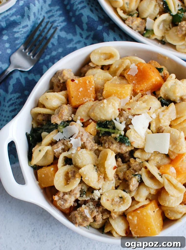 Golden Butternut Squash Pasta with Hearty Sausage 6 Close-up of creamy butternut squash pasta generously topped with fresh Parmesan cheese, ready to be enjoyed.