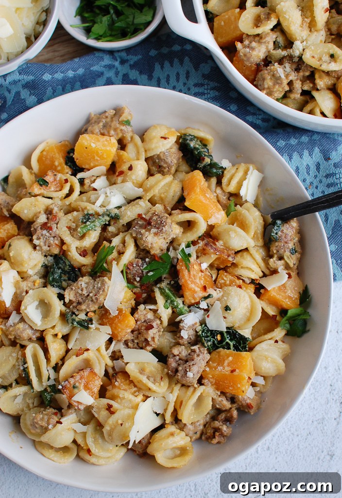Golden Butternut Squash Pasta with Hearty Sausage 7 A fork piercing through strands of creamy butternut squash pasta, showcasing the rich texture and deliciousness of the dish.