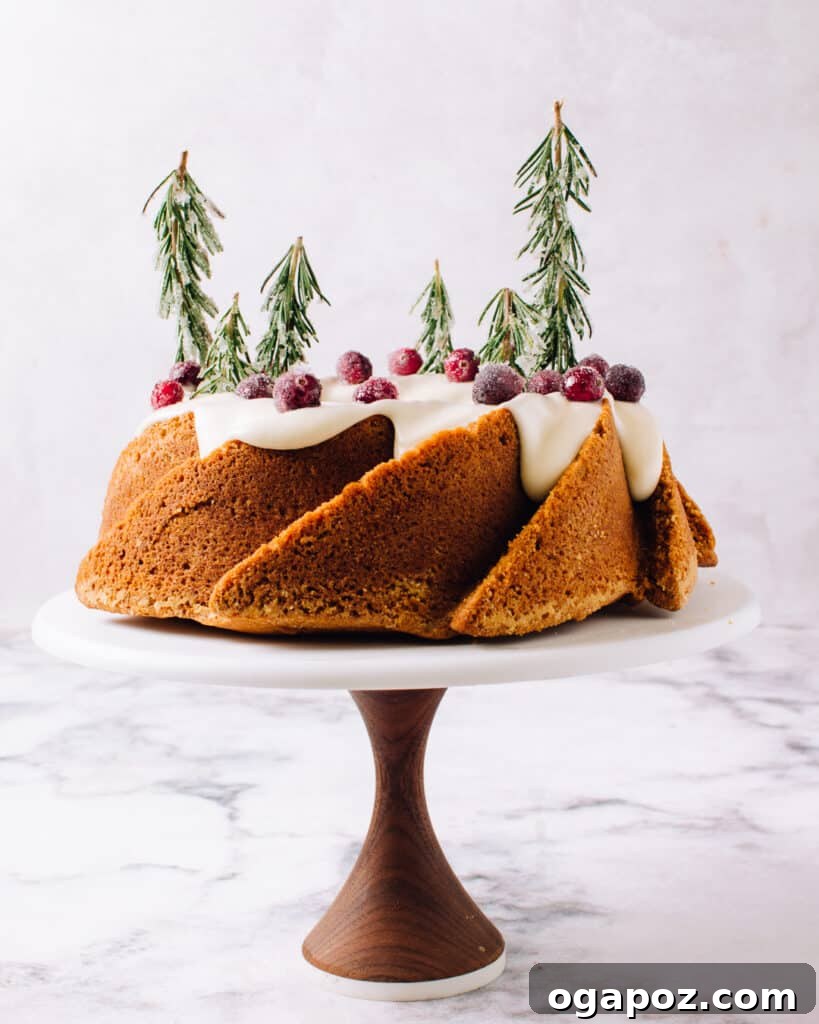 Yuletide Spice Bake 2 Beautifully decorated Holiday Spice Bundt Cake with cream cheese frosting, sugared cranberries, and sugared rosemary on a festive table.