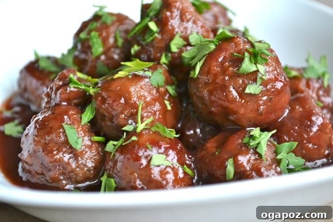 17 Stress-Free Slow Cooker Holiday Meals 4 Appetizer Meatballs with Grape Chili Sauce, garnished with fresh parsley, served from a crockpot.