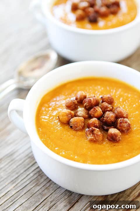 17 Stress-Free Slow Cooker Holiday Meals 6 Creamy Slow Cooker Butternut Squash Soup in a bowl, garnished with maple roasted chickpeas and fresh herbs.