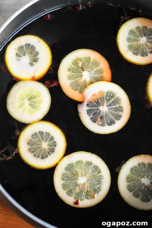 17 Stress-Free Slow Cooker Holiday Meals 8 Warm Holiday Mulled Cranberry Tea with slices of lemon and cinnamon sticks in a clear mug.