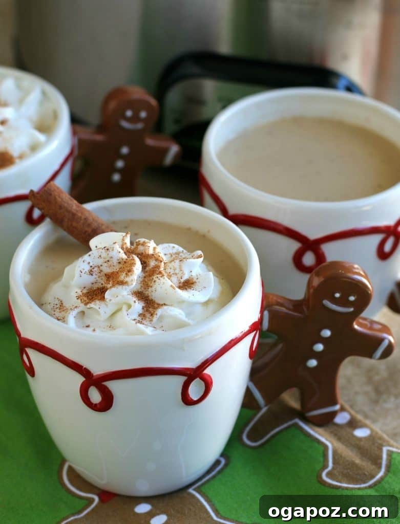 Sip into the Season: 41 Festive Drink Creations 6 Slow Cooker Eggnog Lattes in clear mugs, topped with whipped cream and a cinnamon stick, creating a cozy holiday beverage scene.
