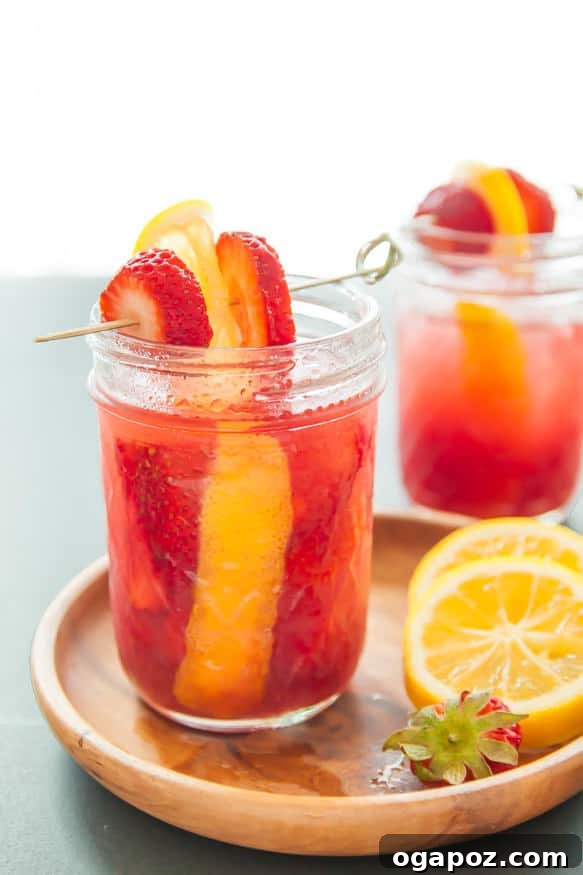 Sip into the Season: 41 Festive Drink Creations 9 A beautiful strawberry moonshine cocktail in a mason jar, garnished with fresh strawberries and mint, capturing a rustic charm.