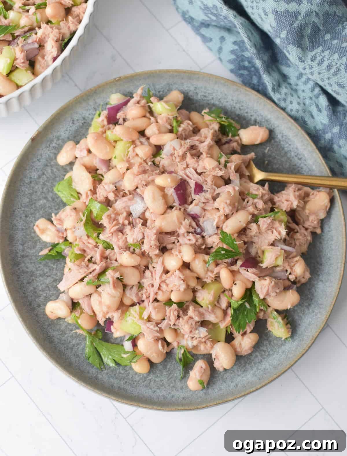 White Bean and Tuna Salad on a blue plate, garnished with fresh herbs, ready to be served.