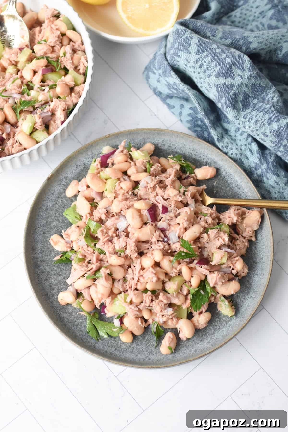 Tuna Bean Salad on a blue plate, garnished with fresh dill and lemon wedges.