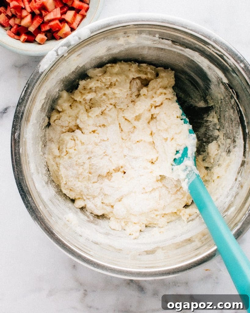 Wholesome Rhubarb Yogurt Muffins 4 Mixing rhubarb muffin batter by hand in a large bowl.