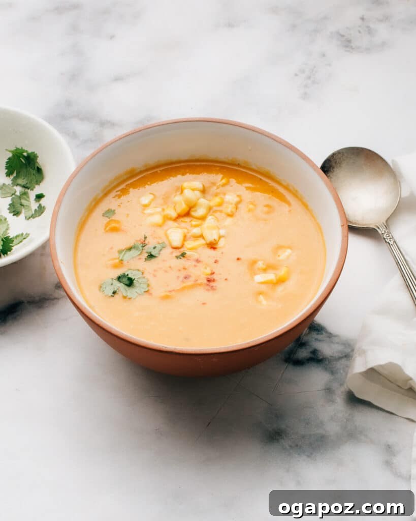 A vibrant bowl of Sweet Potato Soup with Coconut and Corn, garnished with fresh cilantro, inviting and comforting.