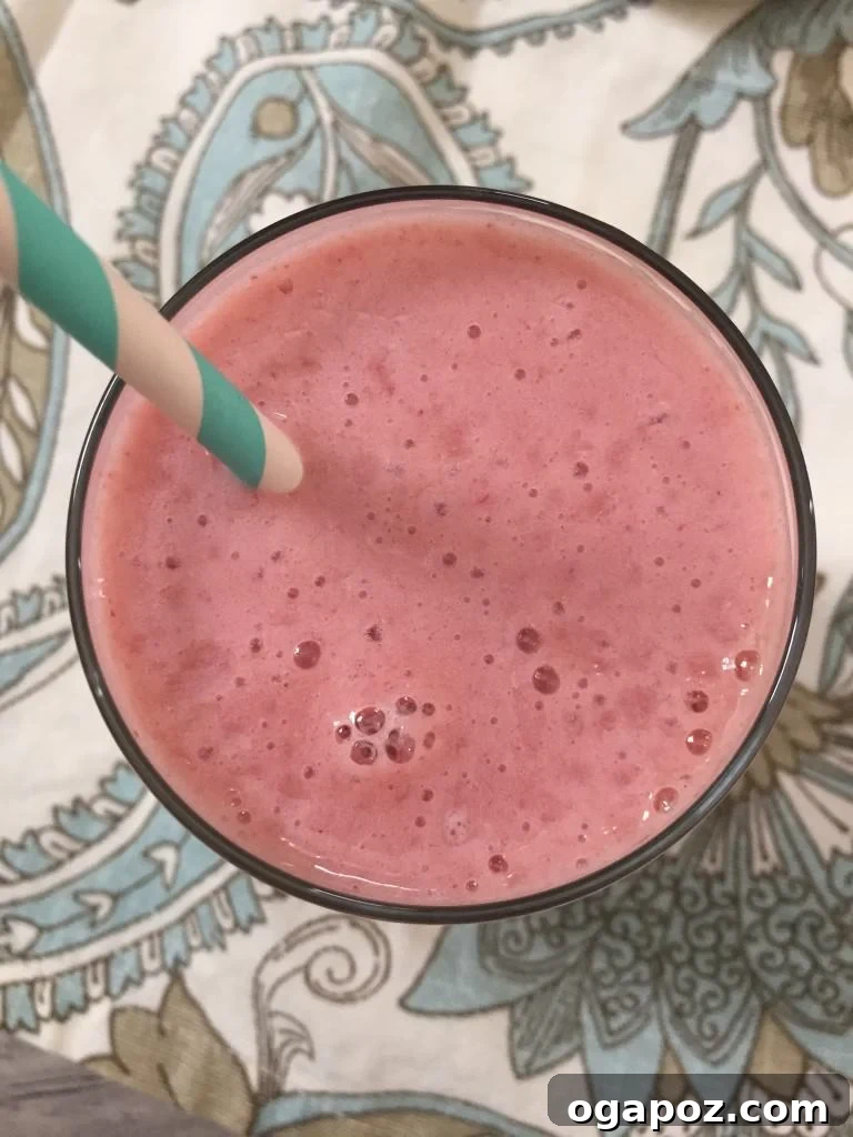 Cantaloupe Berry Bliss 4 An overhead shot of a Strawberry Cantaloupe Smoothie in a glass, with colorful ingredients like fresh strawberries and cantaloupe slices around it.