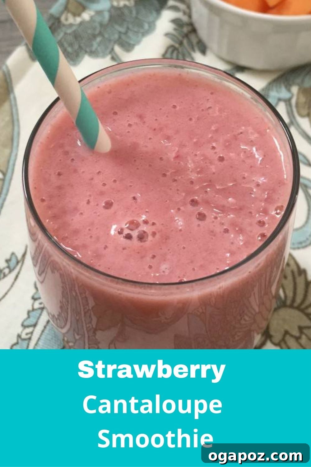 Cantaloupe Berry Bliss 5 A tall glass of Strawberry Cantaloupe Smoothie with a metal straw, placed on a wooden surface with a pink napkin, emphasizing its inviting color and refreshing nature.