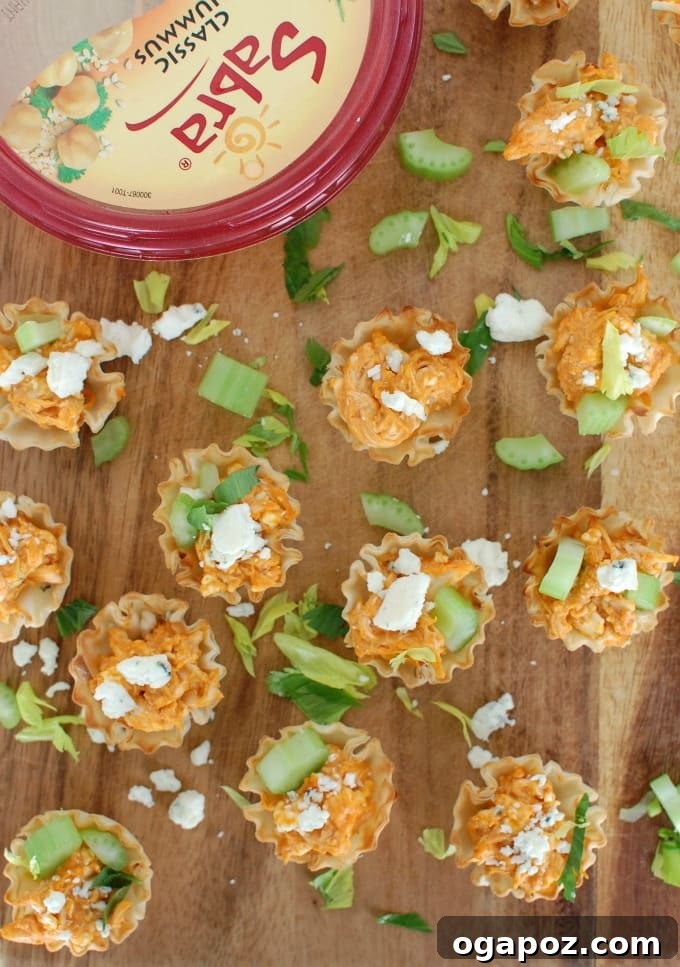Tangy Buffalo Chicken Hummus Poppers 3 Close-up of baked Buffalo Chicken Hummus Bites arranged on a platter, showcasing the golden fillo shells and creamy filling.