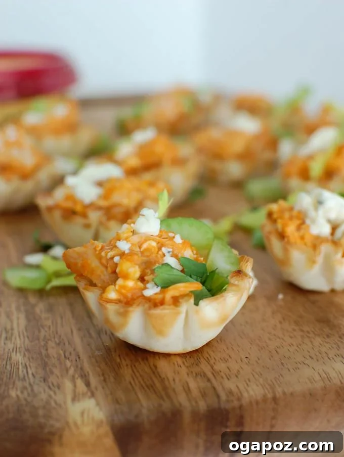Tangy Buffalo Chicken Hummus Poppers 6 Another perspective of the Buffalo Chicken Hummus Bites on a serving tray, garnished with green celery leaves.