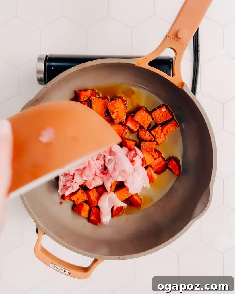Spanish Surf and Turf Paella 3 Adding chicken and chorizo to hot oil in a frying pan, ready to brown.