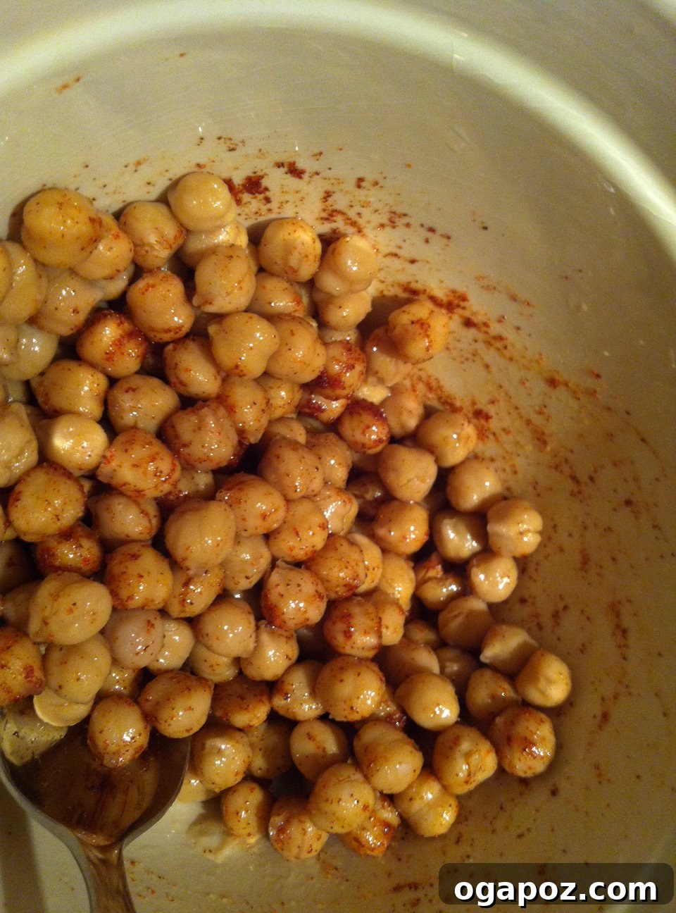 Seasoned Chickpeas Ready for Roasting Chickpeas mixed with olive oil, salt, and cayenne pepper in a mixing bowl
