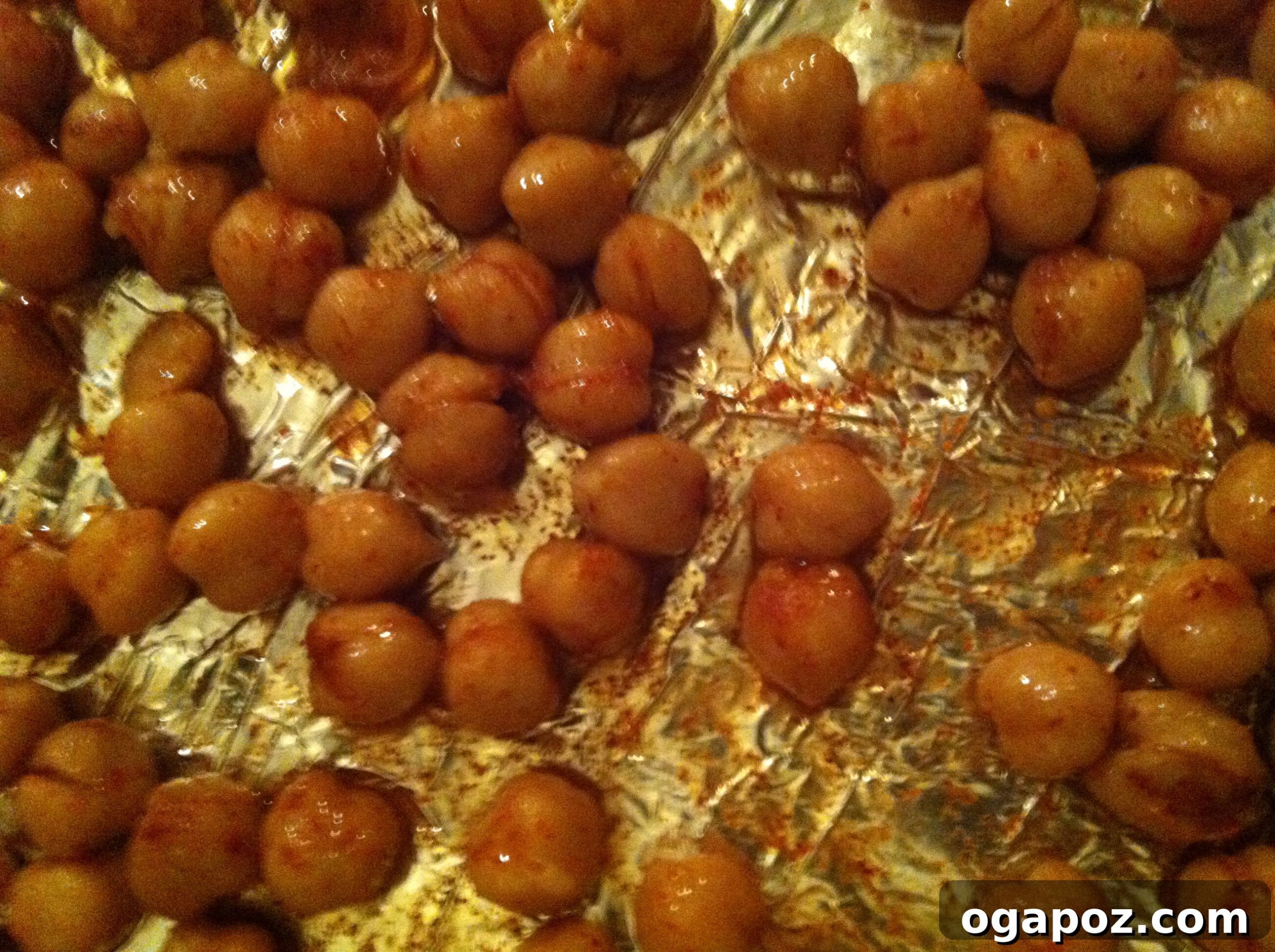 Chickpeas Spread on Baking Sheet Seasoned chickpeas spread evenly on a baking sheet lined with foil