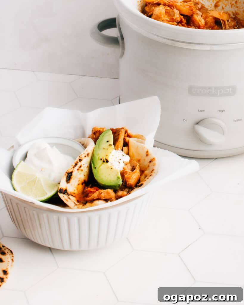 Weeknight Crockpot Chicken Tacos 2 Delicious Shredded Chicken Tacos prepared in a slow cooker, perfect for an easy, healthy, and flavorful weeknight dinner. Topped with fresh cilantro and a squeeze of lime.