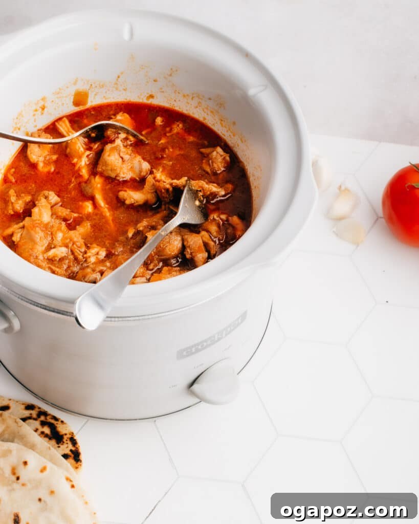 Weeknight Crockpot Chicken Tacos 4 Expert technique for shredding tender cooked chicken using two forks on a cutting board, creating the perfect texture for slow cooker chicken tacos.