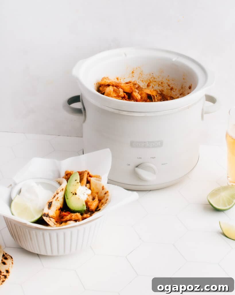 Weeknight Crockpot Chicken Tacos 5 A perfectly assembled Shredded Chicken Taco from the slow cooker, garnished with fresh cilantro, a dollop of sour cream, and a lime wedge, ready to be enjoyed.
