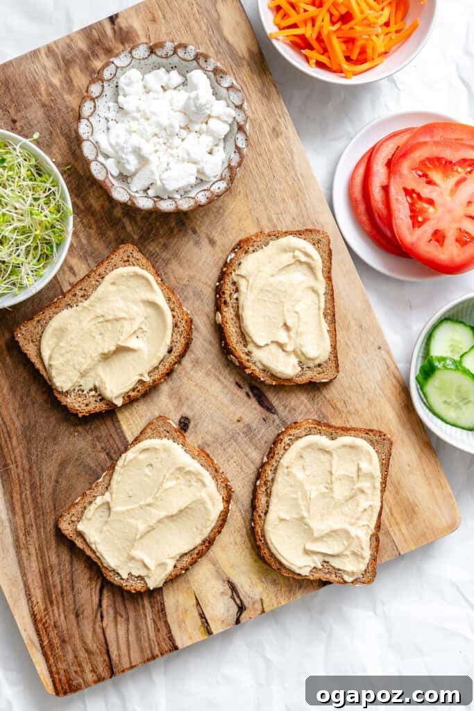 Hummus being spread onto slices of bread for the Mediterranean Vegetable Sandwich.