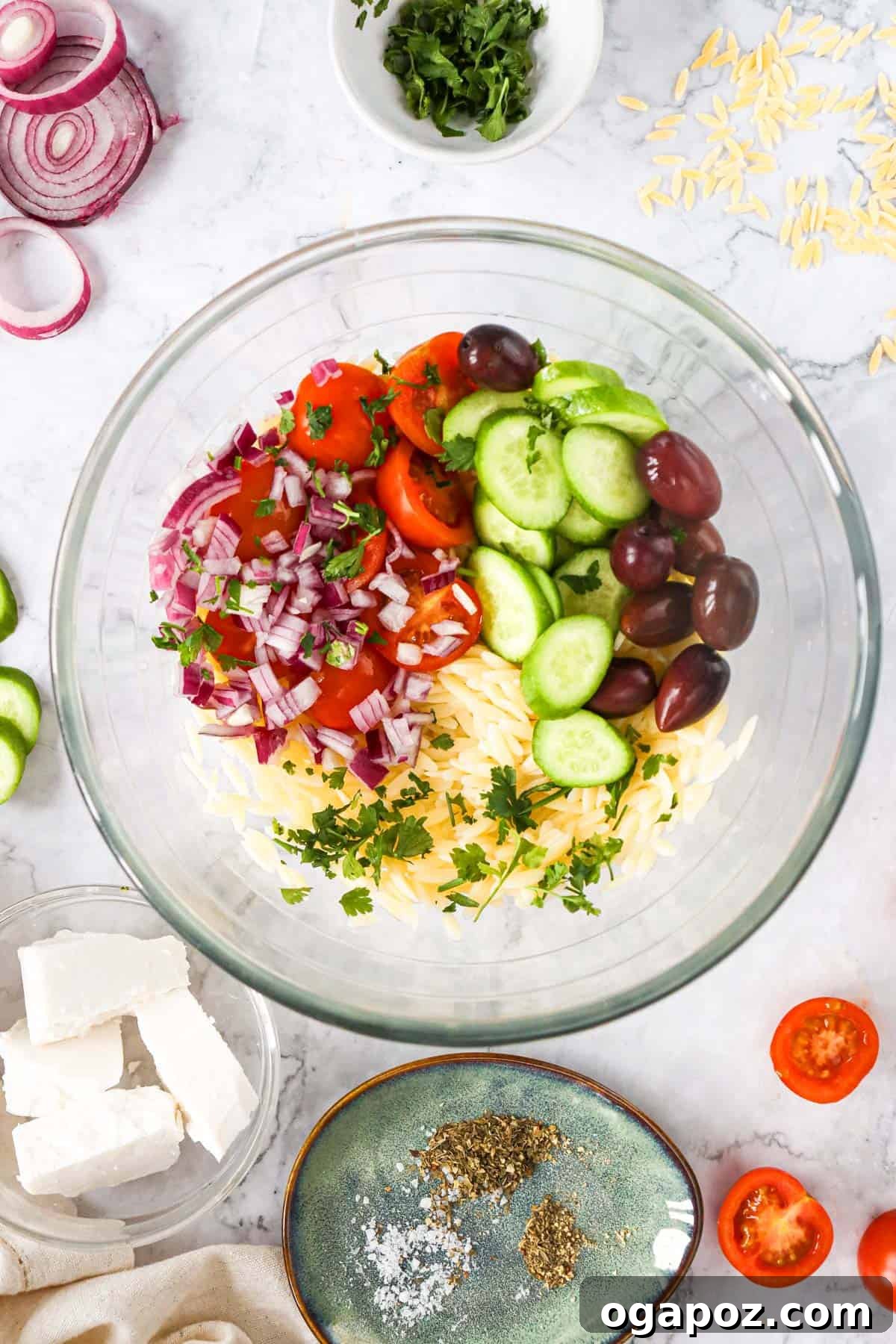Vibrant Grecian Orzo 7 All the Greek Orzo Pasta Salad ingredients mixed together in a large white bowl.