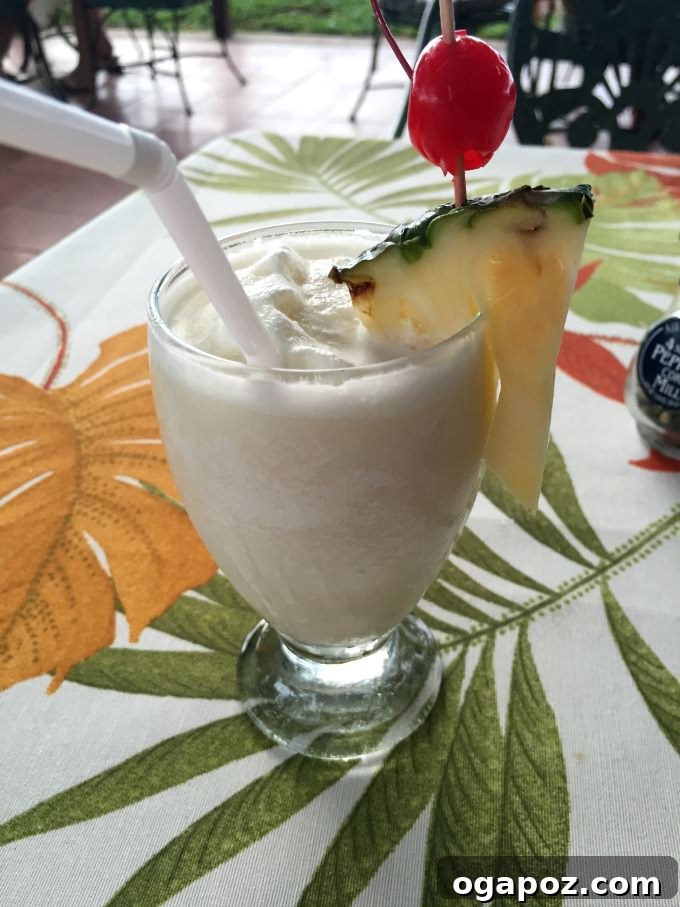 Tamarindo: Costa Rica's Pacific Paradise 18 Tropical Pina Colada drink with pineapple slice and cherry garnish on a wooden table