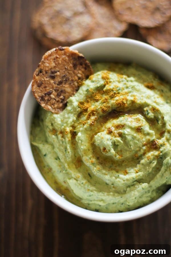Beyond the Bowl: 12 Exciting Hummus Recipes 11 A healthy bowl of vibrant green Roasted Garlic Kale Hummus, garnished with roasted garlic cloves.