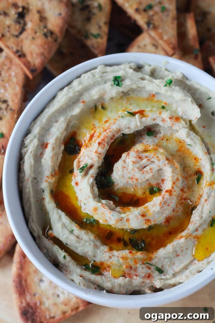 Beyond the Bowl: 12 Exciting Hummus Recipes 4 A vibrant bowl of Roasted Garlic White Bean Hummus, garnished with fresh herbs and a drizzle of olive oil.