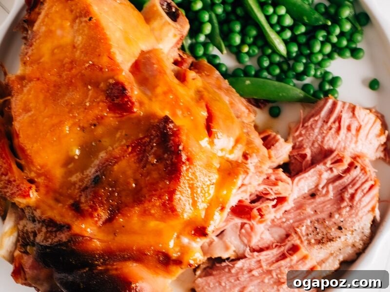 A beautifully glazed pressure cooker ham, served on a platter with green peas, showcasing its inviting appearance.