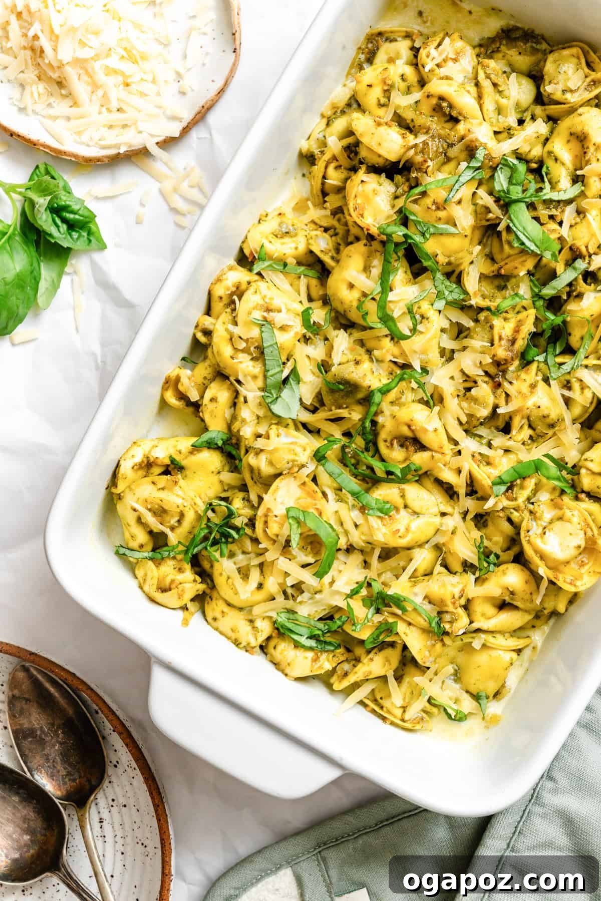 A baking dish filled with golden-brown, cheesy pesto tortellini, fresh from the oven and ready to be served.