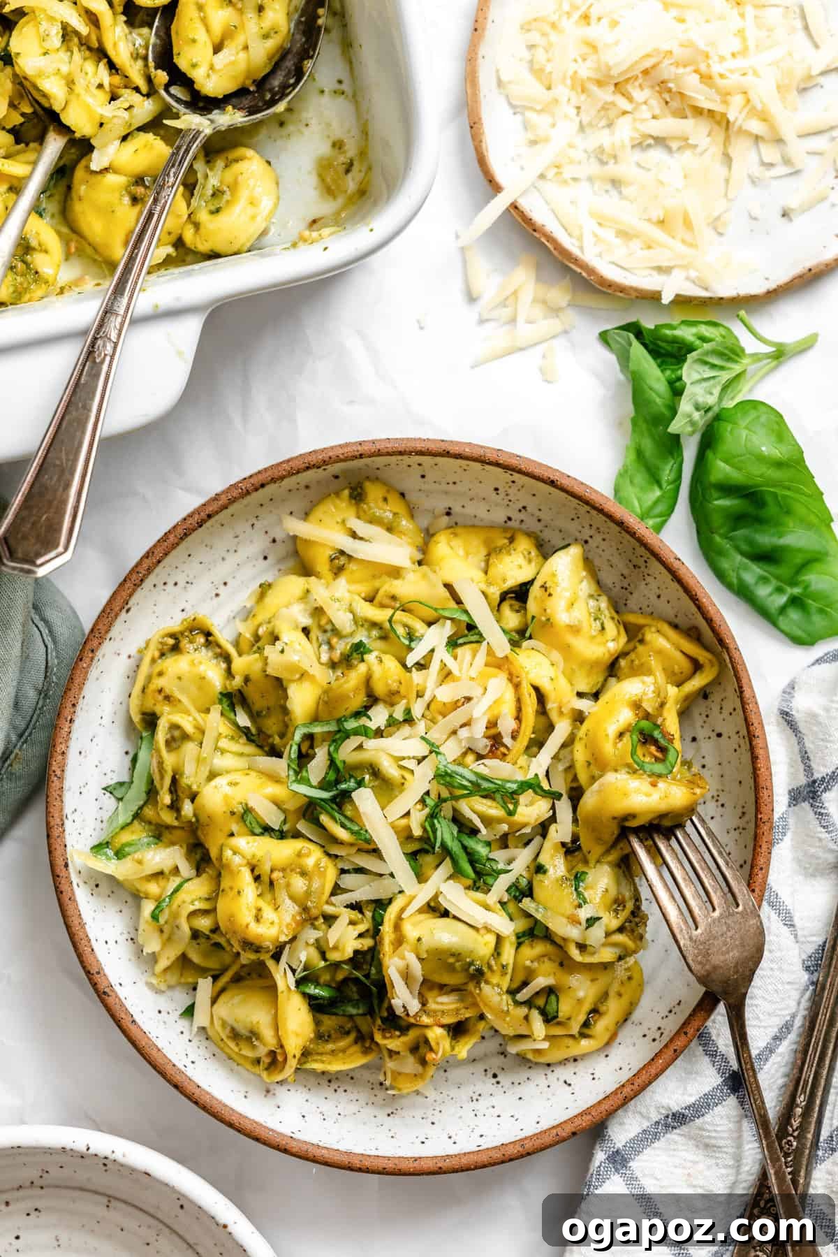 A single serving of freshly baked pesto tortellini in a bowl, garnished with fresh basil leaves and a sprinkle of Parmesan.