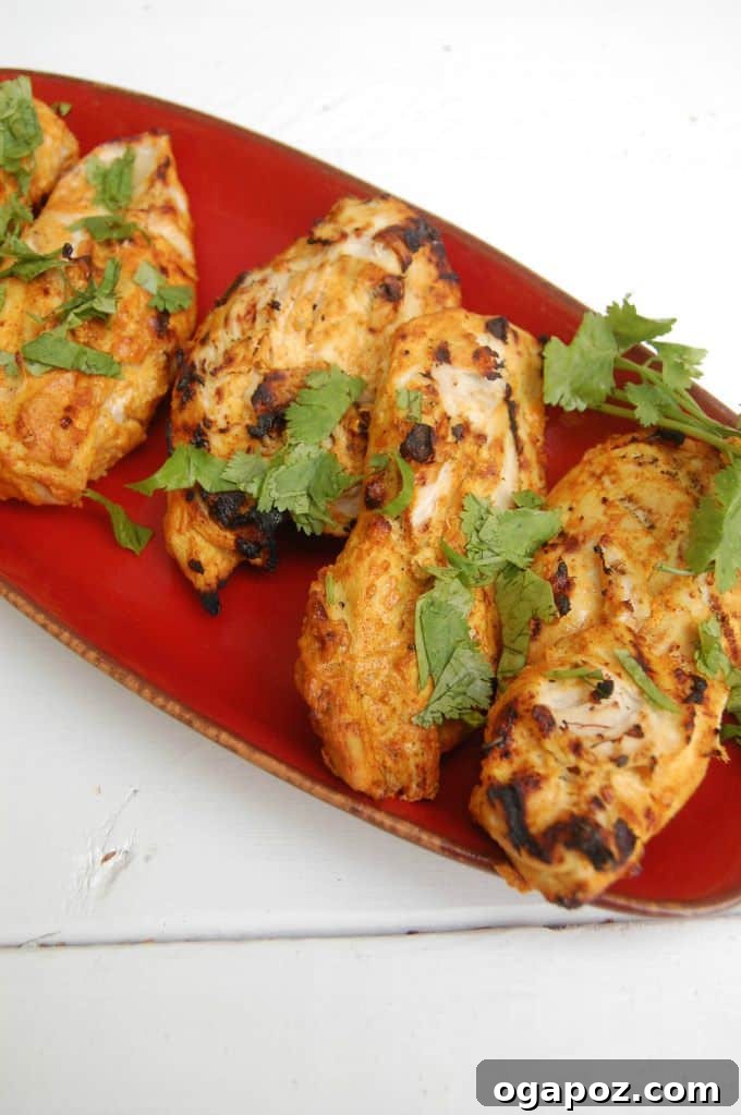 Smoky Tandoori Grilled Chicken 7 Tandoori Grilled Chicken garnished with fresh cilantro and lime wedges on a serving platter.