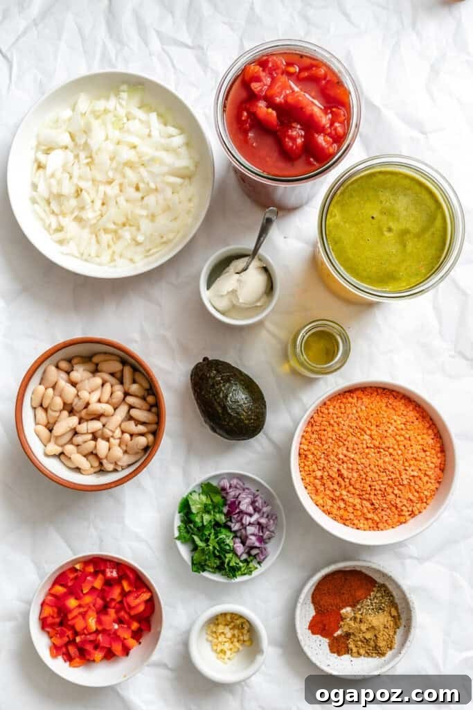 Hearty Lentil Chili 3 A colorful array of fresh ingredients for Lentil Bean Chili, including red lentils, bell peppers, onions, tomatoes, and spices, laid out on a wooden board.