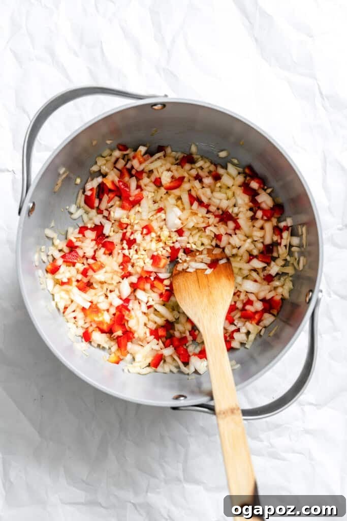 Hearty Lentil Chili 6 Chopped onions and red bell peppers sautéing in olive oil in a large skillet, releasing their aromas.