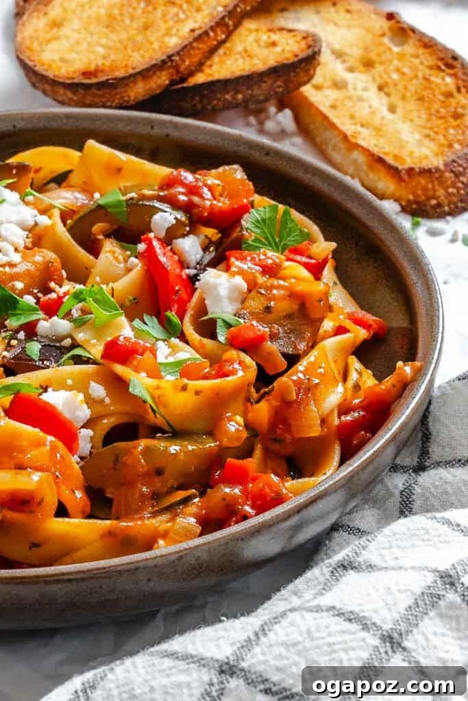 Provencal Garden Pappardelle 2 A vibrant bowl of Ratatouille Pappardelle pasta, showcasing rich red sauce, tender eggplant, green zucchini, and colorful bell peppers, garnished with fresh parsley and feta.