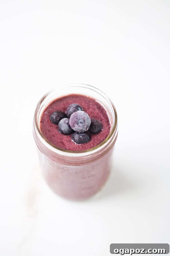 9 Amazing Blueberry Superfood Smoothies 6 A colorful Berry Cherry Pineapple Smoothie presented in a clear glass, vividly highlighting its fresh fruit ingredients and tropical appeal.