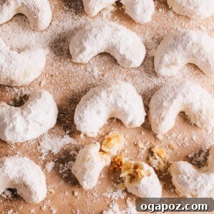 Snow Dusted Kourabiedes A Greek Christmas Classic 13 A batch of Kourabiedes or Greek Christmas Cookies on a surface with one cookie broken, ready for serving and to reveal its tender interior.